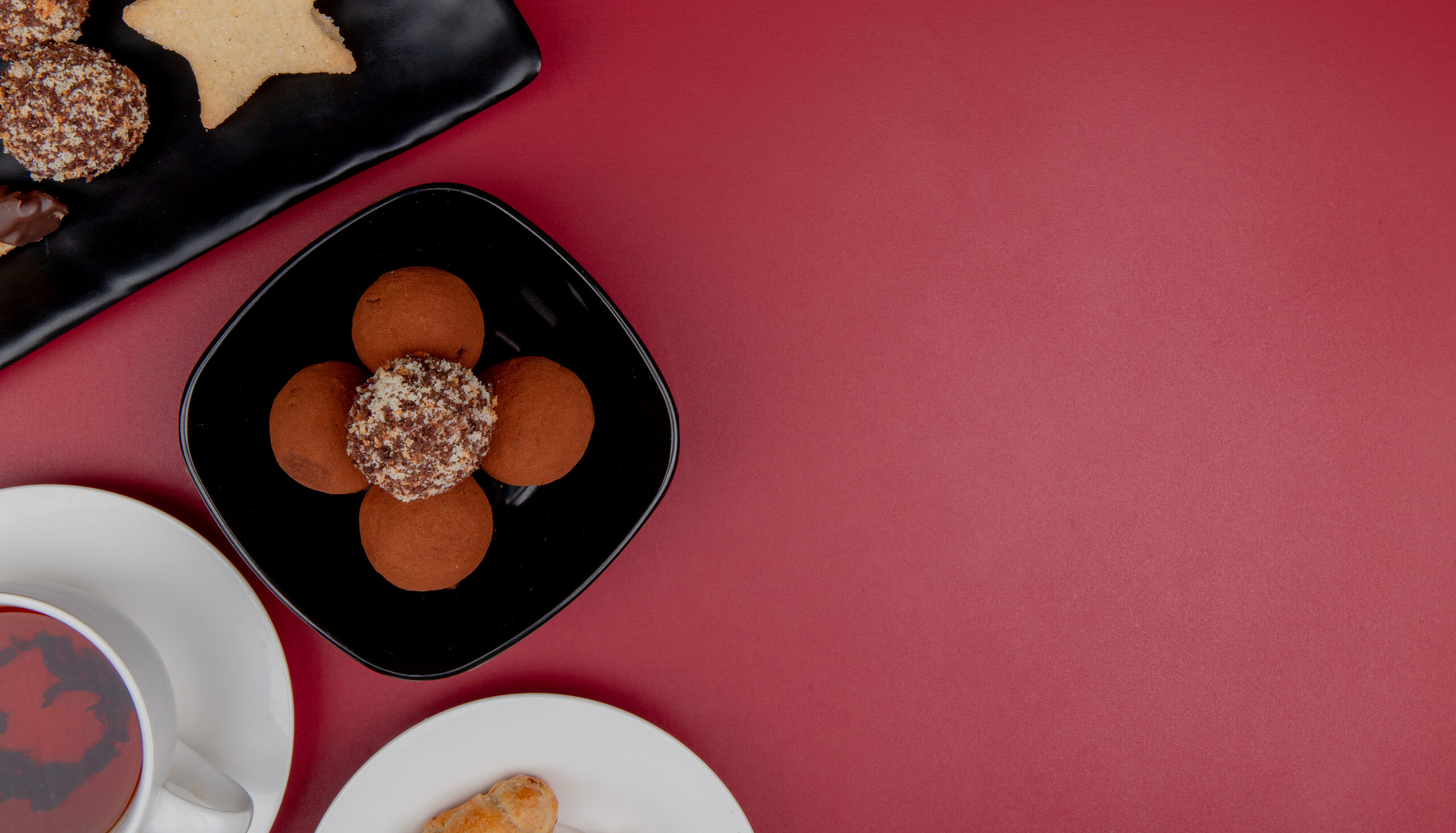 top view of cookies in plate with cup of tea on red background with copy space