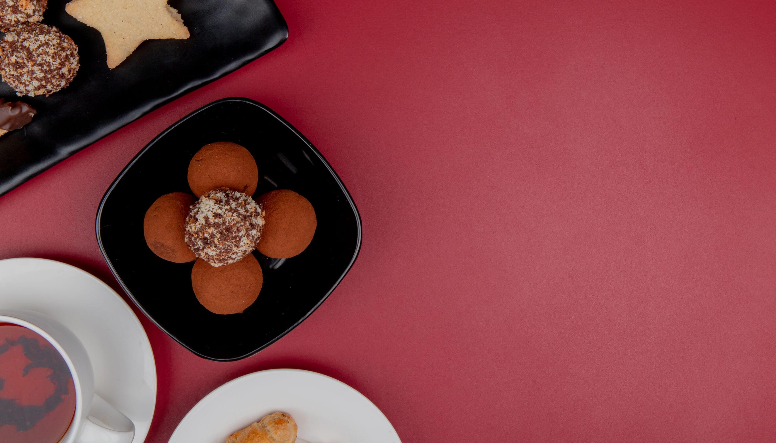 top view of cookies in plate with cup of tea on red background with copy space